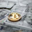 A Bitcoin coin placed on top of US currency notes. A Bitcoin coin placed on top of US currency notes.