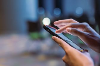 A person using a smartphone in a dimly lit environment, focusing on the screen.