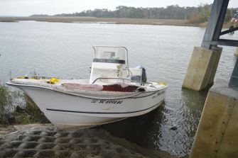 A damaged boat docked at a riverbank, involved in a fatal accident.