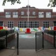 Exterior view of a public school building with a playground visible in front. Exterior view of a public school building with a playground visible in front.