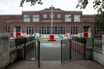 Exterior view of a public school building with a playground visible in front.