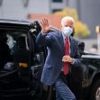 Joe Biden waving while exiting a vehicle, wearing a suit and mask. Joe Biden waving while exiting a vehicle, wearing a suit and mask.