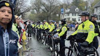 Black-led women's running group, TrailblazHers, and police during the Boston Marathon, with officers forming a barricade at Mile 21.