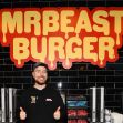 A person standing in front of a "MrBeast Burger" sign, smiling and giving a thumbs up. A person standing in front of a "MrBeast Burger" sign, smiling and giving a thumbs up.