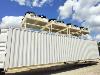 A Bitcoin mining data center with large cooling units on top of a shipping container.