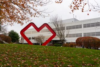 Exterior view of a CVS building featuring a large red heart sculpture in front, surrounded by grass and trees.