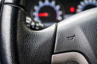 Close-up of a car steering wheel with gauges in the background.