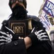 A person holding a Bible while participating in a rally at the Capitol, surrounded by flags and police officers in riot gear. A person holding a Bible while participating in a rally at the Capitol, surrounded by flags and police officers in riot gear.