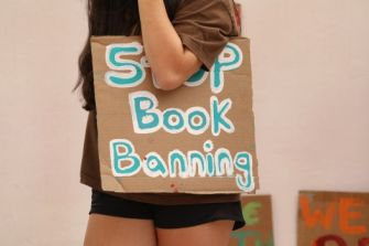 A person holding a cardboard sign that reads "Stop Book Banning."