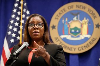 New York Attorney General Letitia James speaking at a press conference with the state seal in the background.