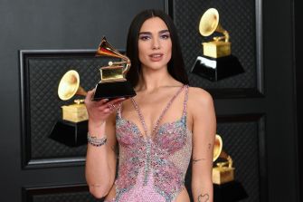 Dua Lipa posing with a Grammy Award at a red carpet event.