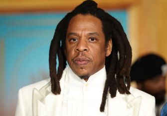 Jay-Z attending an event, dressed in a white suit.