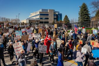 Protesters gather outside a courthouse holding signs related to immigration enforcement and judicial accountability.