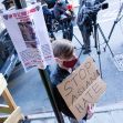 A man holds a sign after an Asian American anti-violence press conference Tuesday outside the building where a 65-year-old Asian woman was attacked in New York City.