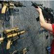 A person examines a display of various assault rifles at an exhibition. A person examines a display of various assault rifles at an exhibition.