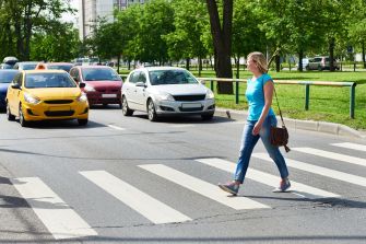 A pedestrian crossing a street while vehicles approach.