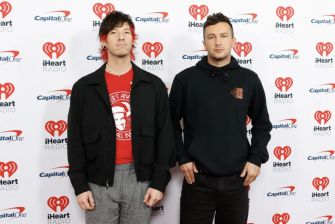 Image of the musical duo Twenty One Pilots at an event, standing in front of a promotional backdrop.