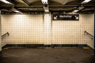 Interior of a New York City subway station with a "Manhattan" sign.