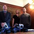 A couple standing with their lawyer at a press conference, discussing their settlement after a kidnapping case. A couple standing with their lawyer at a press conference, discussing their settlement after a kidnapping case.