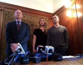 A couple standing with their lawyer at a press conference, discussing their settlement after a kidnapping case.