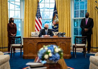 President Biden signs an executive order in the Oval Office, accompanied by Vice President Kamala Harris and Secretary of Defense Lloyd Austin.