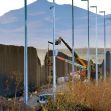 Construction equipment and a partially built section of the border wall between the United States and Mexico, with mountains in the background. Construction equipment and a partially built section of the border wall between the United States and Mexico, with mountains in the background.