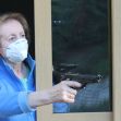 A woman wearing a mask points a handgun out of a window. A woman wearing a mask points a handgun out of a window.