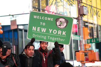 A group of people holding a "Welcome to New York" sign promoting the Green Light NY law, which allows undocumented immigrants to obtain driver's licenses.
