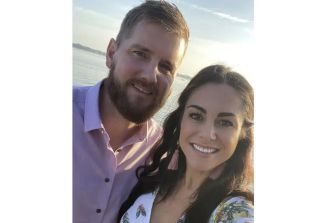 A couple posing for a selfie near the water, smiling together.