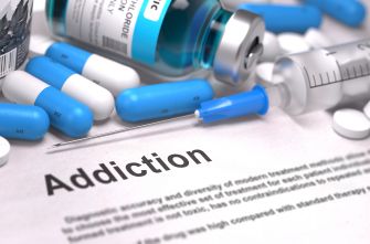 An assortment of drug-related items, including pills, a syringe, and a vial, with the word "Addiction" prominently displayed on a document.