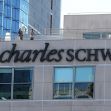 Signage of Charles Schwab building with two people on the rooftop. Signage of Charles Schwab building with two people on the rooftop.