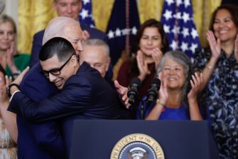 A moment of celebration as President Joe Biden embraces an individual during an announcement regarding new immigration policies, surrounded by supporters.
