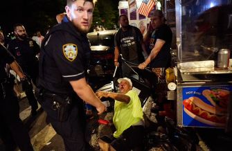 A police officer stands beside an injured hot dog vendor on the ground at a Pride event in Washington Square Park.
