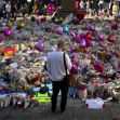 A person stands in front of a large memorial made up of flowers, balloons, and messages honoring the victims of the 2017 Manchester concert bombing. A person stands in front of a large memorial made up of flowers, balloons, and messages honoring the victims of the 2017 Manchester concert bombing.