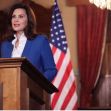 Michigan Governor Gretchen Whitmer speaking at a podium in front of the state flag and a U.S. flag after signing new sex offender amendments into law. Michigan Governor Gretchen Whitmer speaking at a podium in front of the state flag and a U.S. flag after signing new sex offender amendments into law.