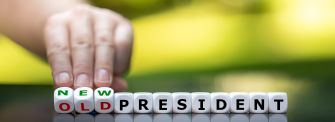 A hand rearranging letter blocks to change "OLD PRESIDENT" to "NEW PRESIDENT."