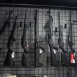 A display of various firearms mounted on a wall in a gun shop. A display of various firearms mounted on a wall in a gun shop.