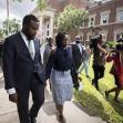 A man and a woman walking together surrounded by media cameras outside a courthouse. A man and a woman walking together surrounded by media cameras outside a courthouse.