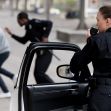 Police officers in pursuit of a suspect, one using a radio while the other chases a fleeing individual. Police officers in pursuit of a suspect, one using a radio while the other chases a fleeing individual.
