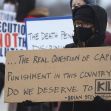 A person holding a protest sign questioning the morality of capital punishment, surrounded by others holding similar signs. A person holding a protest sign questioning the morality of capital punishment, surrounded by others holding similar signs.