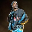 Travis Scott performing at a concert, wearing a colorful shirt and holding a microphone. Travis Scott performing at a concert, wearing a colorful shirt and holding a microphone.