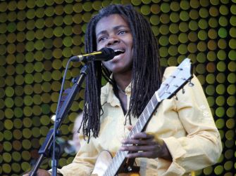 Tracy Chapman performing on stage with a guitar.