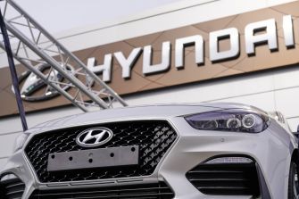 Close-up of a Hyundai vehicle in front of a Hyundai dealership sign.