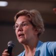 A woman speaking into a microphone while gesturing, with a focus on student loan issues. A woman speaking into a microphone while gesturing, with a focus on student loan issues.