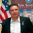 A man in a suit speaking at a press conference, with a flag and a backdrop featuring the Louisiana state emblem. A man in a suit speaking at a press conference, with a flag and a backdrop featuring the Louisiana state emblem.