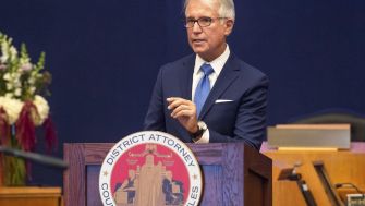 Los Angeles District Attorney George Gascón speaking at an event, with the official seal of the District Attorney's office visible.