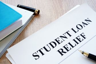 Document labeled "STUDENT LOAN RELIEF" with a pen and notebooks on a wooden surface.