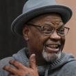 Glynn Simmons smiling while speaking, wearing a gray hat and glasses, reflecting on his wrongful incarceration and recent settlement. Glynn Simmons smiling while speaking, wearing a gray hat and glasses, reflecting on his wrongful incarceration and recent settlement.