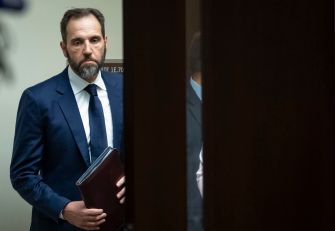 Special Counsel Jack Smith entering a courtroom while carrying a folder, as he announces the dismissal of federal cases against President-elect Trump.