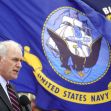 A man speaking at a podium in front of a United States Navy flag. A man speaking at a podium in front of a United States Navy flag.